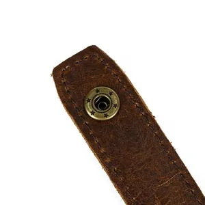 Close-up detail of vintage brown genuine leather wallet strap with bronze snap button.