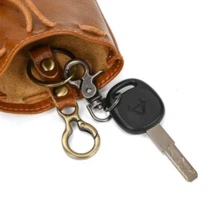 Close-up detail of vintage vegetable-tanned leather coin pouch with metal key rings and clasps.