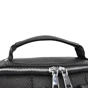 Close-up detail of black leather backpack top handle and durable metal dual zippers for men.