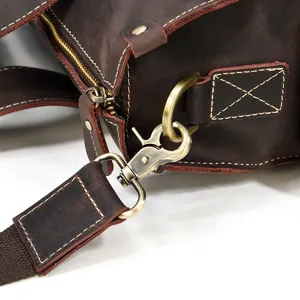 Close-up view of vintage leather bag hardware, featuring solid metal hook and neat stitching.