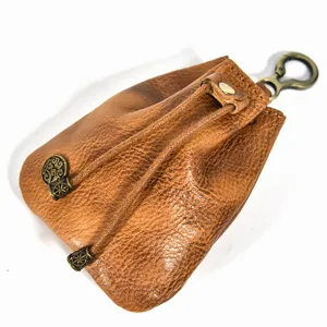 Detailed shot of retro brown leather coin pouch with drawstring and vintage brass metal decor.
