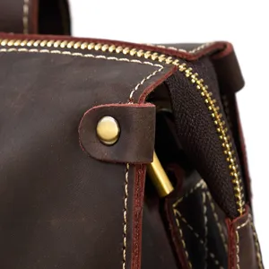 Close-up detail of retro brown crazy horse leather bag with stitching and brass hardware.