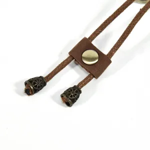 Close-up detail of retro brown braided leather cord with antique metal end caps and slider.