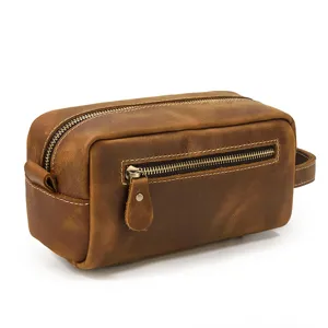 Detail shot of brown genuine leather toiletry bag with zipper pocket and metal hardware close-up.