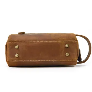 Close-up detail of vintage genuine leather toiletry bag showing metal bottom feet and side handle.