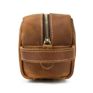 Close-up detail of the durable metal zipper and side handle on a vintage brown leather bag.