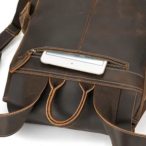 Close-up detail of dark brown genuine leather backpack back pocket and reinforced strap stitching.