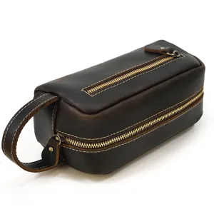 Detailed view of genuine leather toiletry bag with durable golden zippers and side handle.
