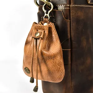 Close-up of vintage handmade veg-tanned leather coin purse, mini drawstring pouch detail.