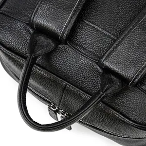 Close-up detail shot showing black leather backpack handle and zipper craftsmanship.