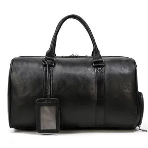 Detail view of the black leather travel duffel bag with handles, luggage tag and side pocket.