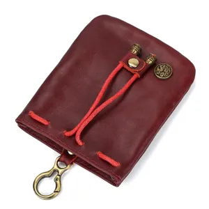 Mini vintage vegetable-tanned leather coin purse with metal clasp and red drawstring.