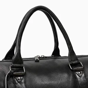 Detailed close-up view of black leather travel duffel bag handle showcasing premium texture.