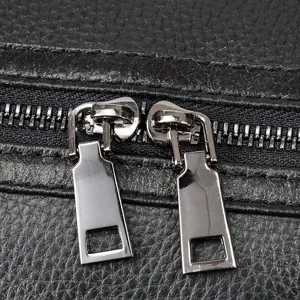 Leather travel duffel bag detail showcasing sturdy metal double zippers and fine stitching.