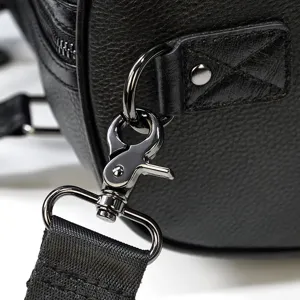 Close-up detail shot of black leather travel bag metal hardware, durable clasp and strap.
