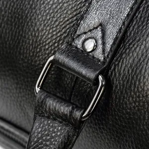 Leather travel bag detail shot showing premium black cowhide texture and sturdy metal hardware.