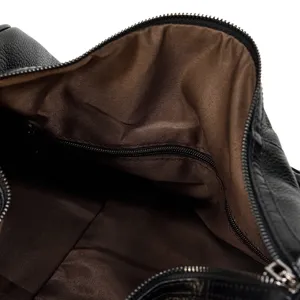 Black leather travel bag interior detail showing brown lining and zipper pocket.
