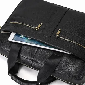 Leather briefcase detail showing black cowhide texture, metal zippers, and tablet pocket.