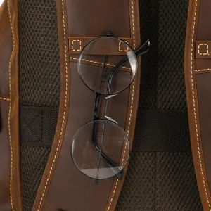 Close-up of leather backpack shoulder strap with glasses holder, showing retro crazy horse texture.