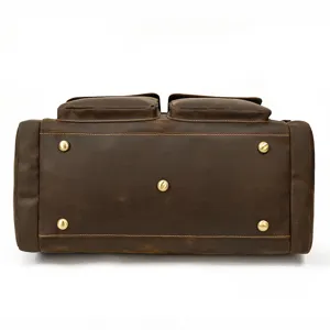 Dettaglio del fondo della borsa da viaggio in pelle con piedini metallici e texture vintage.