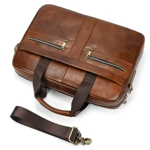 Brown leather briefcase detail view, metal zipper pockets, durable top handles and strap.