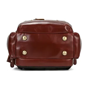 Detailed bottom view of vintage brown leather travel backpack showing four metal feet.