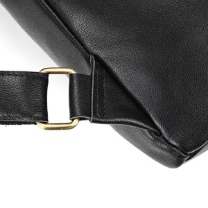 Detail shot of the black leather backpack strap and metal buckle, showing fine stitching.