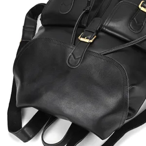 Detailed view of black leather backpack buckle strap showing premium grain texture.