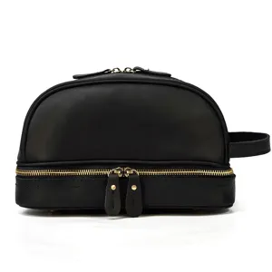 Close-up detail of the black genuine leather double-layer toiletry bag with gold zipper.
