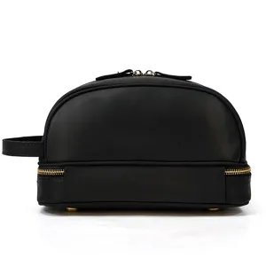Black genuine leather double layer toiletry bag featuring gold zippers and side handle.