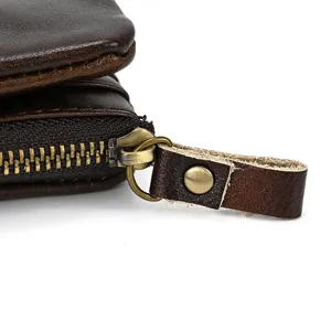 Close-up detail of vintage cowhide leather wallet zipper and metal pull tab, brown.