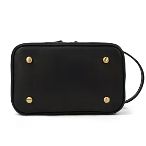 Black genuine leather toiletry bag detail, metal feet, portable handle, compact cosmetic pouch.