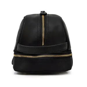 Close-up of black genuine leather toiletry bag, dual layer gold zippers, premium detail shot.
