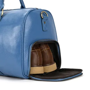 Detailed close-up view of the blue leather travel bag highlighting the bottom shoe storage section.
