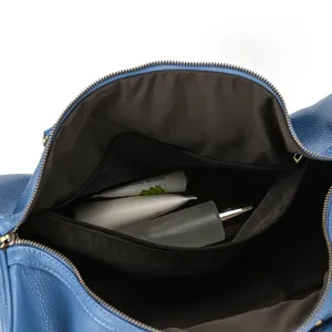 Interior detail view of blue leather travel duffel bag showing interior zipper pocket.