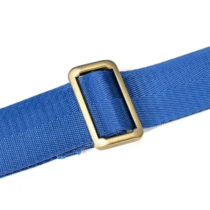 Detailed view of durable blue woven strap with brass metal buckle for luggage bags.