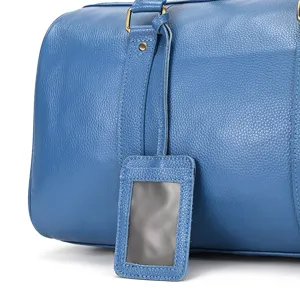Blue leather travel duffel bag detail showing luggage tag and sturdy hardware craftsmanship.