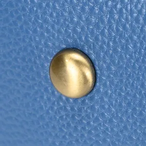 Close-up detail of genuine leather travel bag bottom metal stud, high quality cowhide texture.