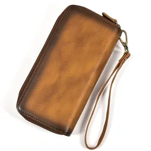Detalle de la cartera larga de cuero auténtico vintage con acabado desgastado y correa de muñeca.
