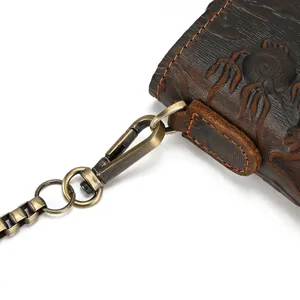 Close-up detail of vintage embossed leather wallet with antique bronze metal chain and clasp.