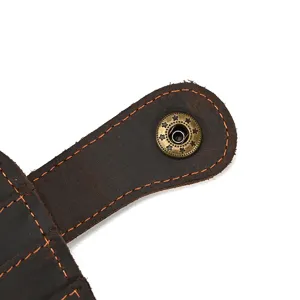 Close-up detail of vintage genuine leather wallet snap button with contrast orange stitching.