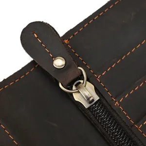 Close-up detail of retro brown genuine leather wallet zipper and contrast stitching.