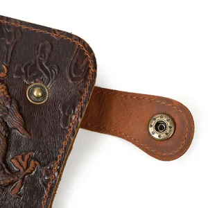 Détail de portefeuille en cuir vintage avec motif de dragon gaufré et bouton pression.