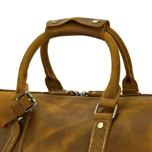 Gros plan sur la poignée, la quincaillerie et les coutures du sac de voyage en cuir.