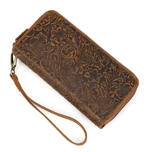 Close-up view of vintage embossed leather long wallet with wrist strap and metal zipper.