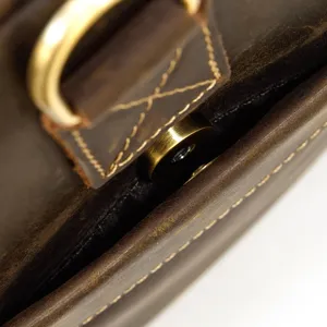 Dettaglio in primo piano della borsa in pelle vintage con anello a D e chiusura.