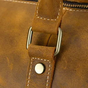 Gros plan de details d'un sac de voyage en cuir avec anneau metallique et coutures fines.