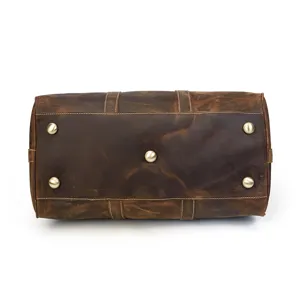 Détail inférieur du sac de voyage en cuir vintage avec pieds en métal robustes et coutures