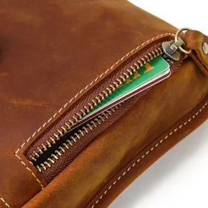 Close-up detail view of genuine leather bag zipper pocket, showing retro brown cowhide texture.