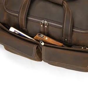 Detalle de bolsa de viaje vintage de cuero, bolso de lona marrón con múltiples bolsillos.